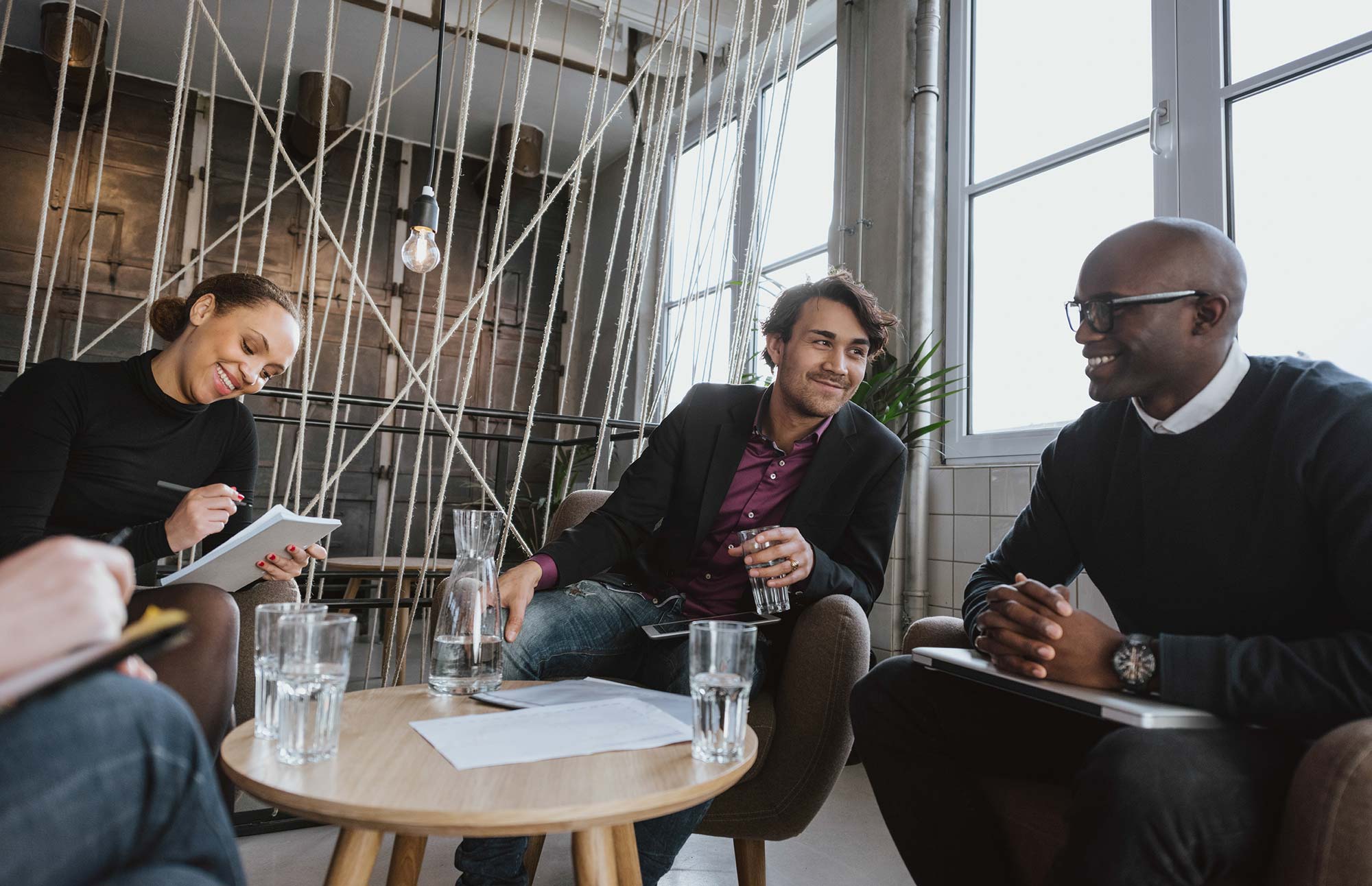 Four people sitting at a table with water glasses smiling