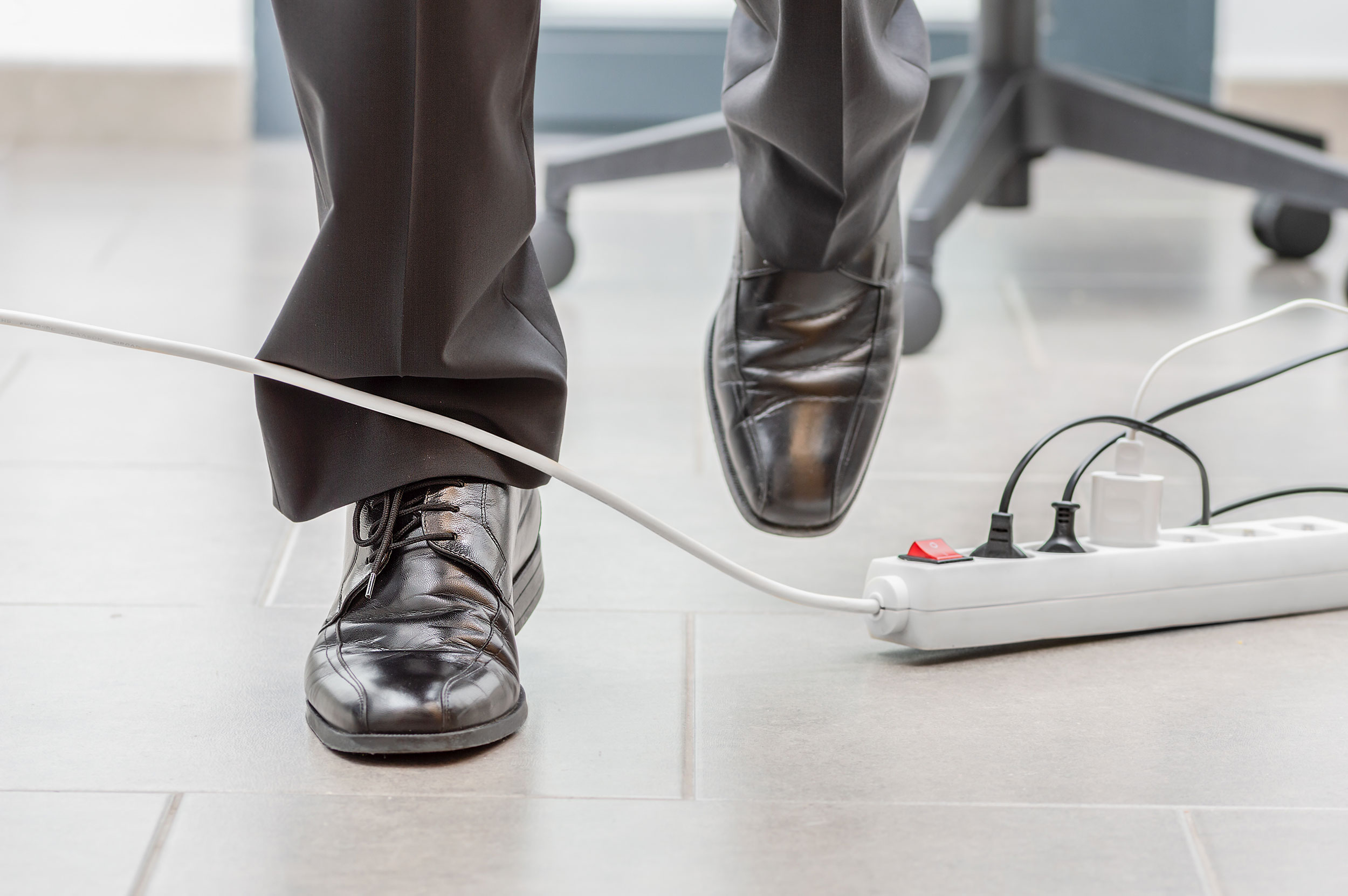 A man is about to trip on a carelessly-placed cord