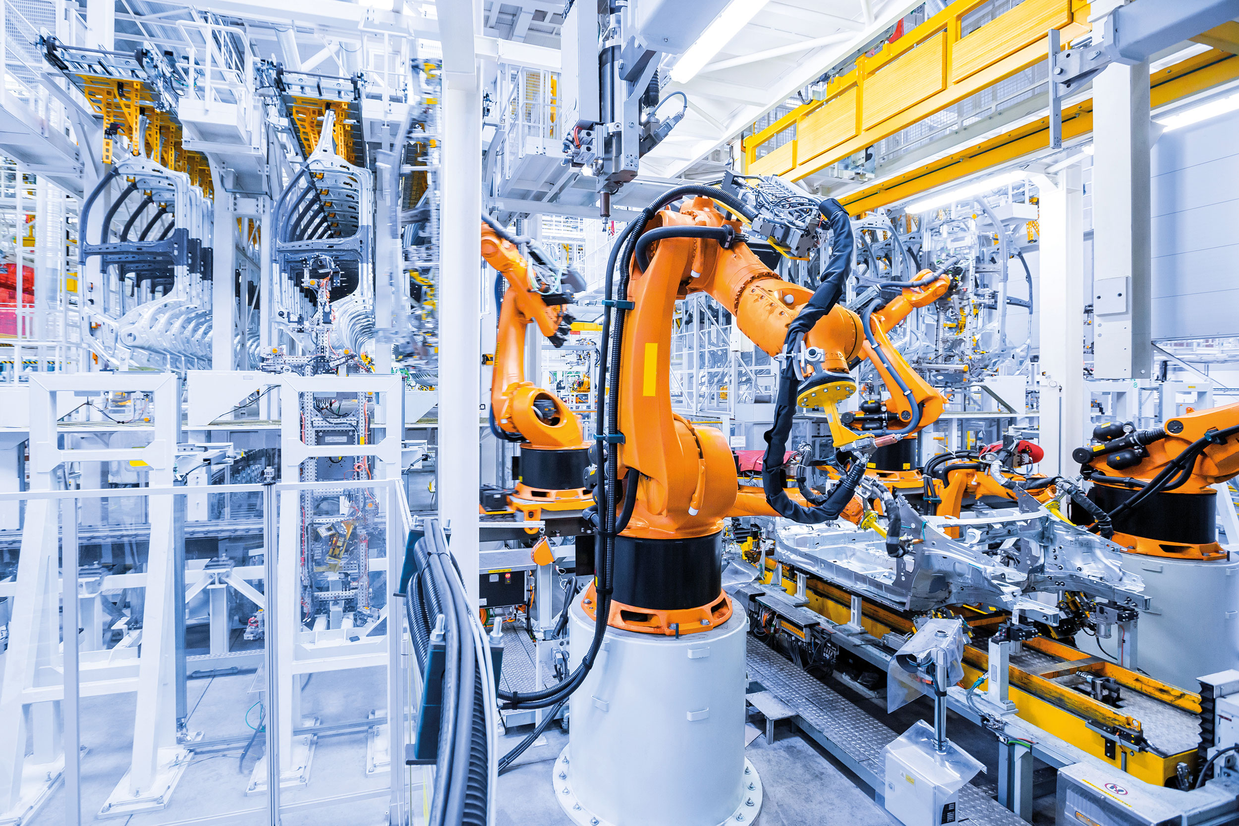 A robotic arm assembles a vehicle chassis