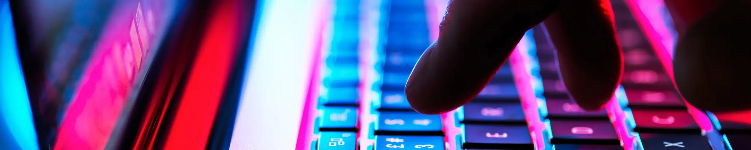 Fingers touch a laptop keyboard in eerie light