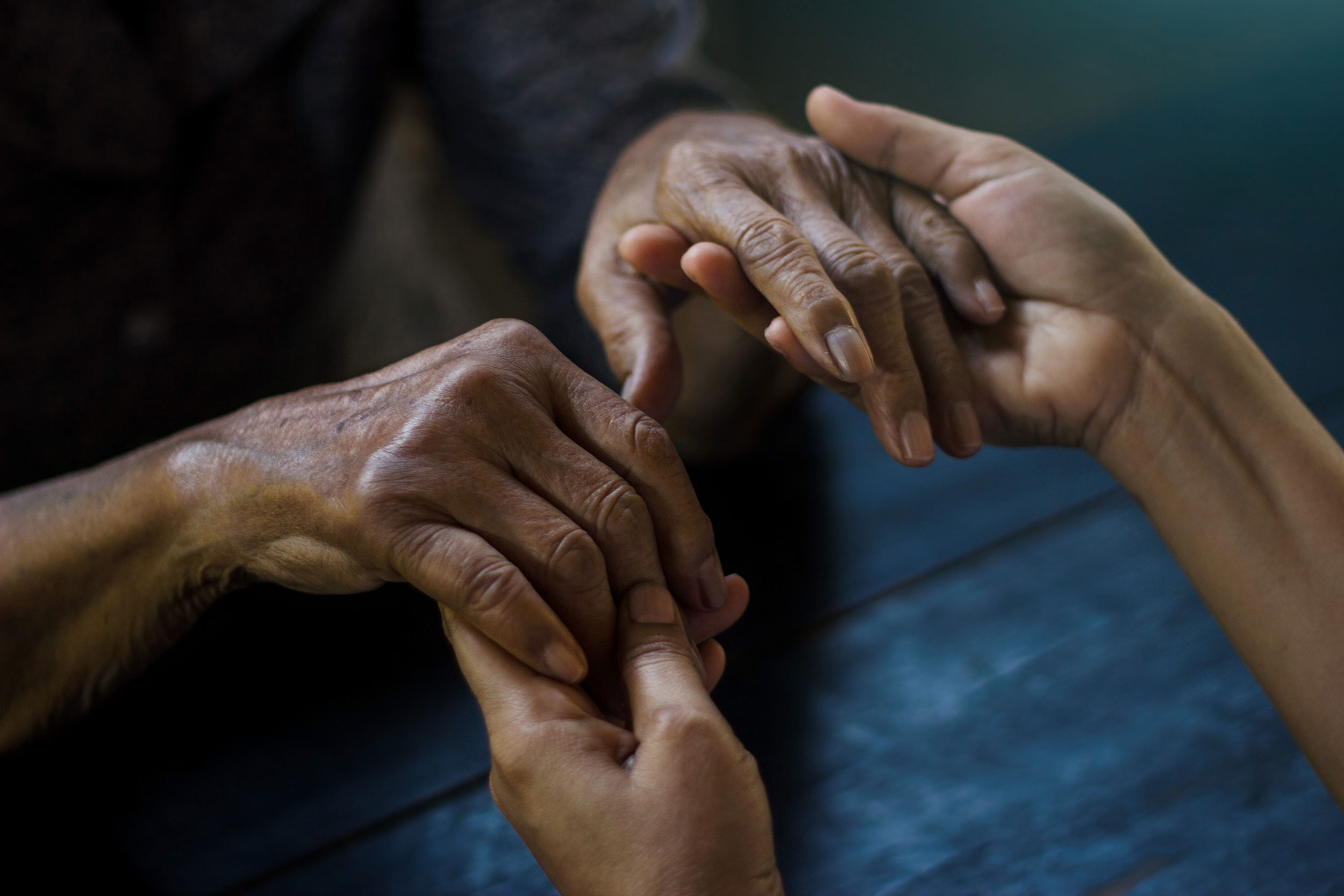 The hands of the young embrace the hands of the elderly